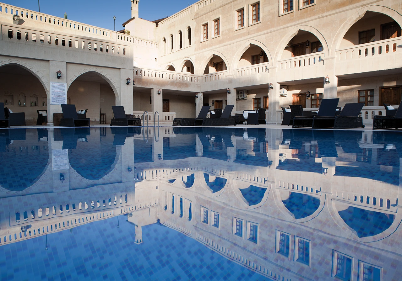 Taş kemerli otel cephesinin açık havuzdaki yansıması